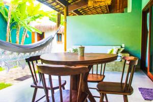 a wooden table and chairs on a patio with a hammock at Tropicália Chalés Boutique in Pipa