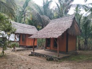 a small house with a thatched roof next to some palm trees at ATUH GARDEN Silent Glamping in Klungkung