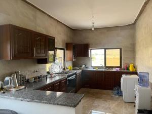 a kitchen with wooden cabinets and a counter top at Guest house in Ghawr alsafi in Aş Şāfī
