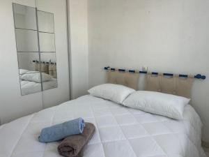 ein weißes Bett mit zwei Kissen und einem Handtuch darauf in der Unterkunft Notre-Dame-de-Monts (85) - Appartement de vacances 45m² environ - 4 personnes - FR-1-540-294 in Notre-Dame-de-Monts