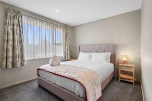 een slaapkamer met een groot bed en een raam bij Modern 2-Bedroom Oasis Just Steps from the Beach in Christchurch
