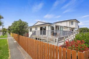 een wit huis met een hek ervoor bij Modern 2-Bedroom Oasis Just Steps from the Beach in Christchurch