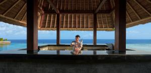 a person sitting on a table in a room with the ocean at Holiday Inn Resort Bali Canggu by IHG in Canggu