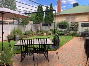 a patio with a table with chairs and an umbrella at HOME STAY on HIGH King Bed -- Private Home with Private Bathroom in Swan Hill