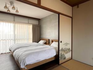 a bedroom with a large bed and a window at TRAVEL&BOOK HOTEL HULATONCABIN TAKAMATSU in Takamatsu
