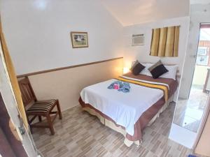 a hotel room with a bed and a chair at Sandstorm Lodge and Cafe in Puerto Galera