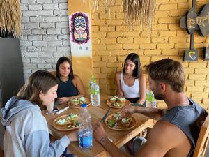 Un gruppo di persone seduti intorno a un tavolo che mangiano cibo di Tiki bar hostel ella a Ella