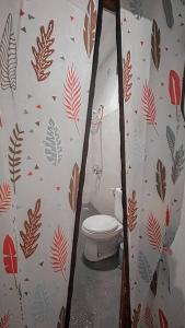 a bathroom with a toilet in a room with leaves on the wall at Conscioushouse 3BR near Seminyak up to 10pax in Legian