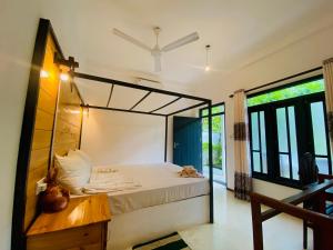 una camera da letto con un letto grande e alcune finestre di Rekawa Turtle Gate Hotel a Tangalle