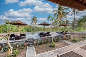 a resort with a pool and chairs and umbrellas at MT Penida Bungalow in Nusa Penida
