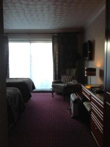 a hotel room with a bed and a couch and a window at Balmoral Lodge Hotel in Southport