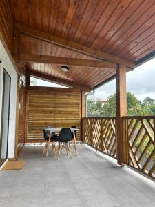 a wooden pavilion with a table and chairs on a patio at Logement Émeraude in Sainte-Rose