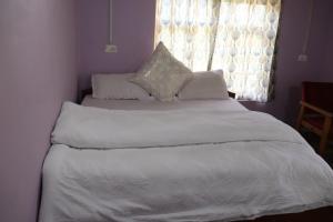a bedroom with a bed with white sheets and a window at Hotel Tserap View in Padam