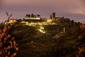 a castle sitting on top of a hill at night at La Monastica Resort & Spa in Borgo a Buggiano