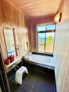 a bathroom with a bath tub and a window at ジェムスティーイン川奈 in Ito +32 photos