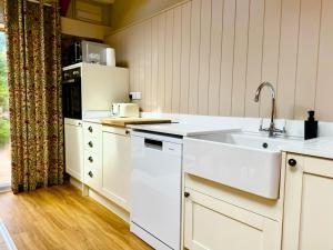 a kitchen with a sink and a refrigerator at Hideaway Cottages - Greenacres Estates in Tenby +38 photos