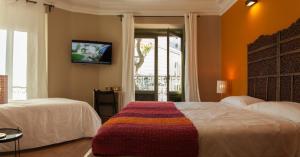 Un dormitorio con dos camas y un televisor en la pared. en AbraCadabra Suites, en Madrid