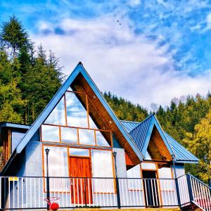 una piccola casa con il tetto e le finestre blu di Snowind Cottages a Kūfrī