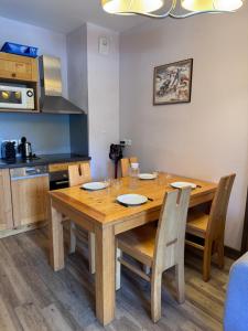 a wooden dining room table with chairs and a kitchen at Superbe appartement ski aux pieds in Risoul