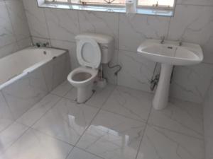 a white bathroom with a toilet and a sink at Arcon Guest House in Vanderbijlpark