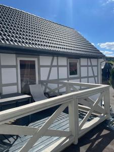 a white house with a deck and a chair at Im Fachwerk – Wohlfühlen, Entspannen & Wandern im Grünen in Gladenbach