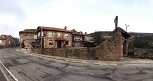 an old stone building on the side of a street at Hostal Cholo in Brañosera