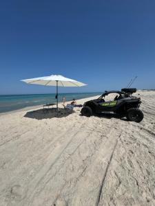 an atv parked on the beach with an umbrella at Résidence Wissem in Ḩammām al Ghazzāz
