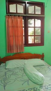 a bed in a green room with a window at Hotel Kawsar Syariah in Negara