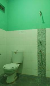 a bathroom with a toilet and a green wall at Hotel Kawsar Syariah in Negara +65 photos