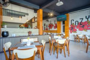 a restaurant with wooden tables and white chairs at Triizz Hotel Semarang in Semarang