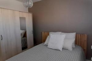 Un dormitorio con una cama con almohadas blancas y un espejo. en La PLage, en Port-la-Nouvelle