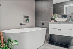 a bathroom with a white tub and a sink at Hobart Luxury Family Home with Spa & Fire Pit, Sleeps 8 in Sorell