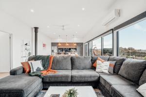 a living room with a gray couch with pillows at Hobart Luxury Family Home with Spa & Fire Pit, Sleeps 8 in Sorell