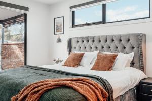 a bedroom with a large bed with a gray headboard at Hobart Luxury Family Home with Spa & Fire Pit, Sleeps 8 in Sorell +59 photos