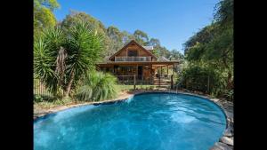 a house with a large pool in front of a house at Rainbow Valley Bunkhouse in Marraweeney