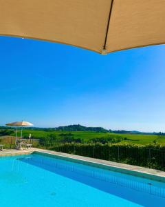 a swimming pool with an umbrella and a view at Relais Castello di Razzano in Alfiano Natta