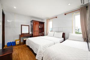 a hotel room with two beds and a mirror at Gia Hoa Airport Hotel in Ho Chi Minh City