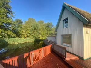 a house with a deck next to a body of water at Bootshaus am Inselseekanal in Güstrow