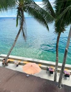 an umbrella sitting under two palm trees next to the ocean at White Knight Double Family Room in San Juan