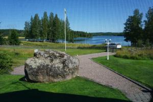una grande roccia appoggiata sull'erba vicino a un lago di Tranquil Lakeside Cottage Retreat i Garpenberg a Garpenberg Altre 15 foto
