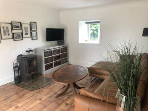 ein Wohnzimmer mit einem Sofa, einem Tisch und einem Herd in der Unterkunft Cottage in heart of Perthshire in New Scone