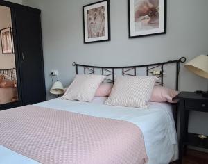 ein Schlafzimmer mit einem Bett mit weißen Laken und rosa Kissen in der Unterkunft Villaplaya Fontefría in Boiro