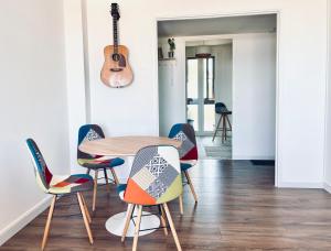 a table and chairs in a room with a guitar at Grand Bleu, Vue sur Lac, Cosy et Chic WIFI Centre ville, Plage in Istres