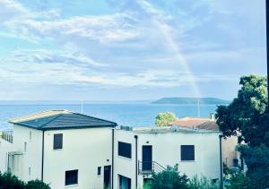 a rainbow over a white building and the ocean at Grand Bleu, Vue sur Lac, Cosy et Chic WIFI Centre ville, Plage in Istres