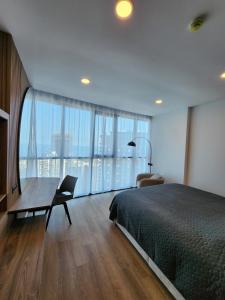 a bedroom with a bed and a desk and large windows at Sea View Plaza Batumi Centre in Batumi