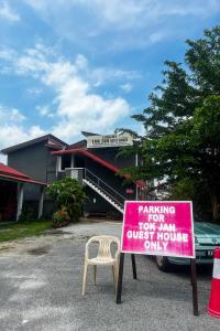 a pink sign in front of a building with a chair at Langkawi Tok Jah Guest House Pantai Cenang in Pantai Cenang