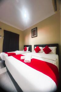 two beds in a room with red and white pillows at Langkawi Tok Jah Guest House Pantai Cenang in Pantai Cenang