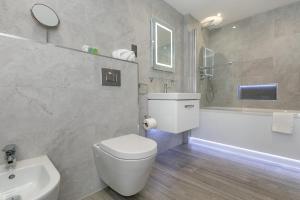 a bathroom with a toilet and a tub and a sink at Maple Lodge in Earley