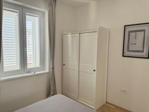a white cabinet in a room with a window at Apartment Block Two in Šibenik