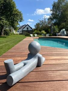 a statue of a person laying on a table next to a swimming pool at Le Cottage in Lasne
